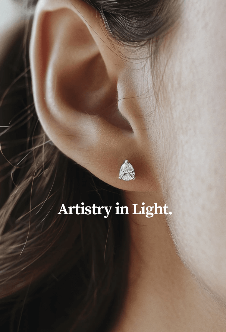 Close-up of a woman's ear wearing a pear-shaped diamond stud earring